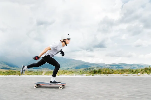 Młody ostatnich wypycha nogę na jego longboard nad szosą — Zdjęcie stockowe