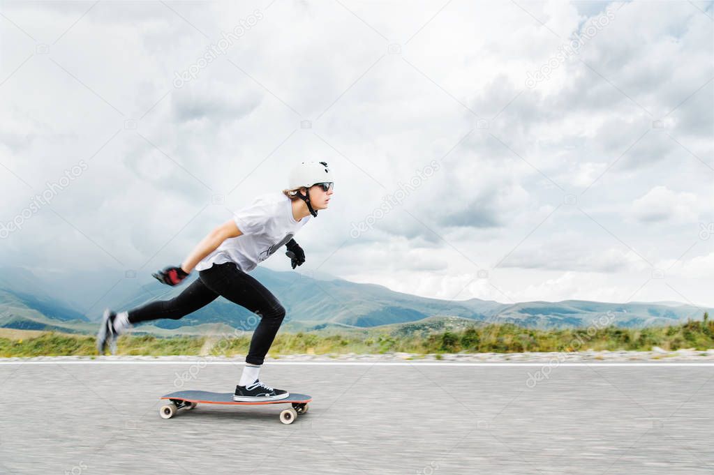 The young Longboarder pushes his foot out on his longboard over the country road