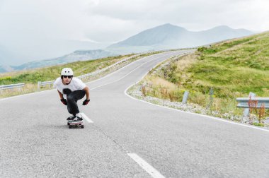 Kask içinde genç bir adam, yağmur altında yüksek hızda bir ülke yolda sürme