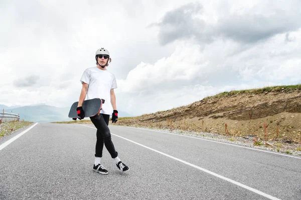 Ein junger Mann - ein Skater, der in Erwartung eines Rennens auf einer Landstraße steht — Stockfoto