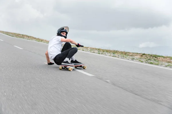 A young guy action makes a slide on a longboard in the resort area of the city — Stock Photo, Image