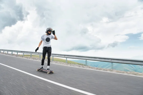 Een jonge kerel in een full-face helm is rijden op een landweg op hoge snelheid in de regen — Stockfoto