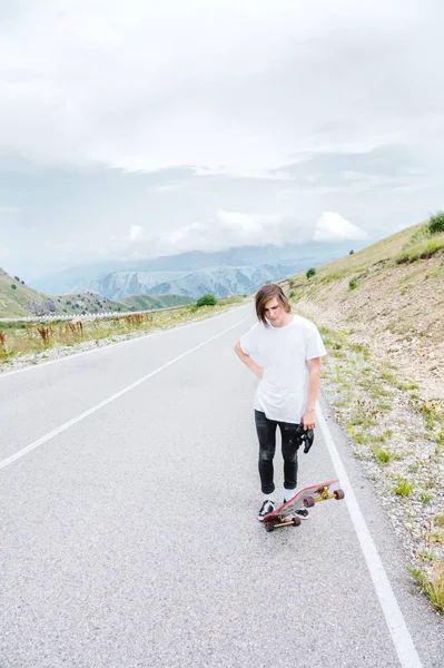 A young guy - a skater standing in anticipation of a race on a country road — Stock Photo, Image