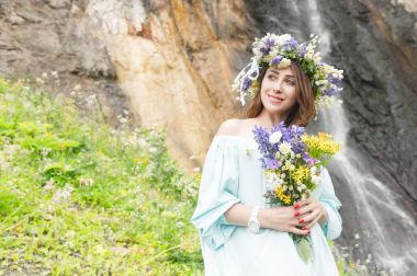 Bir çelenk kafasını ve bir buket çiçek bir şelale karşı onun elinde olan bir kız portresi