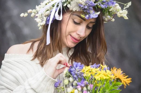 Retrato de uma menina com uma coroa de flores na cabeça e um buquê de flores nas mãos contra uma cachoeira — Fotografia de Stock