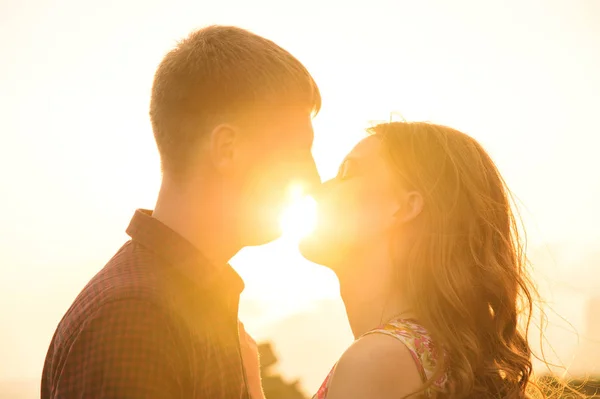 Молода щаслива пара цілується в природі проти заходу сонця . — стокове фото