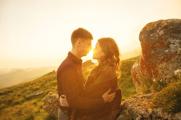 Joven pareja feliz besándose en la naturaleza contra el sol poniente al atardecer . — Foto de Stock