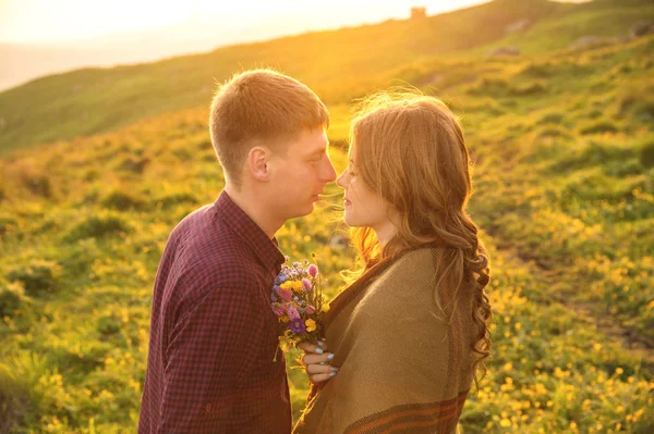 Молодая счастливая пара целуется на природе против заката солнца . — стоковое фото