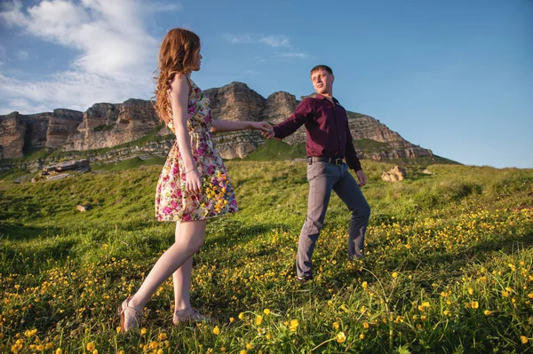 Casal jovem. O cara leva uma garota encaracolada com um buquê de flores . — Fotografia de Stock