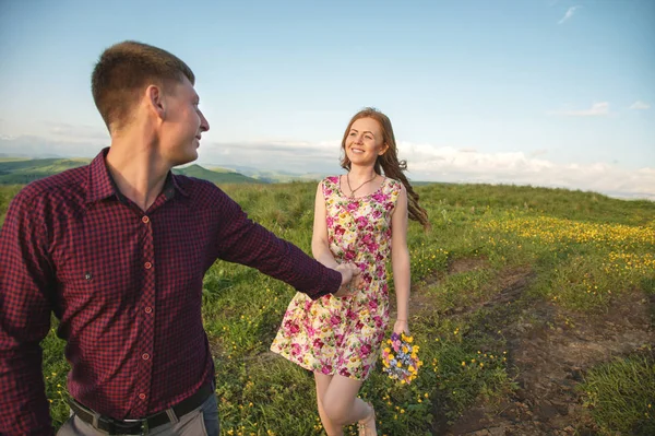 Молодая супружеская пара. Парень ведет кудрявую девушку с букетом цветов . — стоковое фото