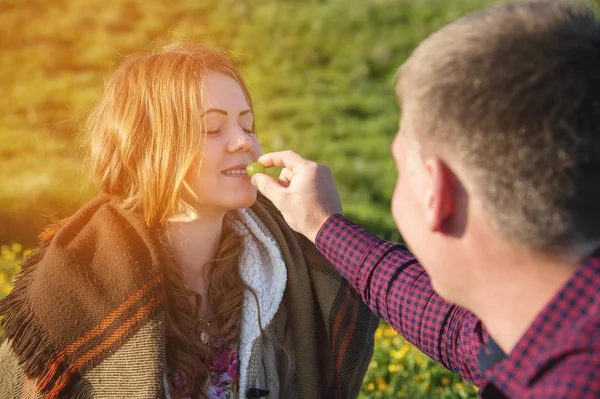 Um jovem casal em um piquenique alimenta uns aos outros com uma seringa — Fotografia de Stock