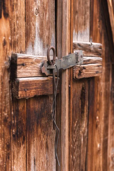 Old simple lock on a wooden door closed with a metal pin rustic latch on an old door made of wood — Stock Photo, Image