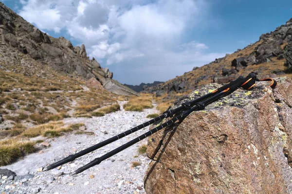 Palos profesionales para escalar una montaña cerca de una piedra en un camino de alta montaña contra un cielo azul y nubes blancas . —  Fotos de Stock