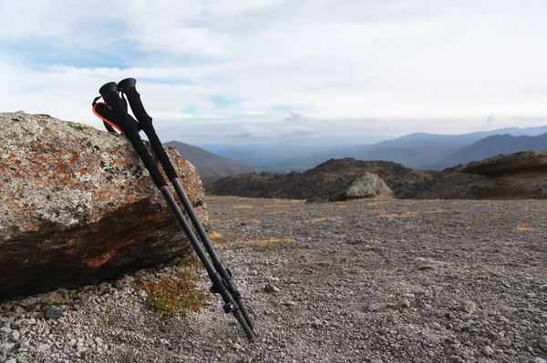 Professional stokken voor het beklimmen van een berg in de buurt van een steen op een hoge bergpad tegen een blauwe hemel en witte wolken. — Stockfoto