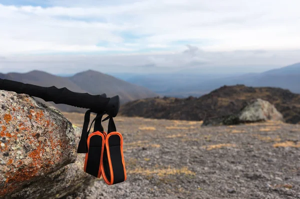Mavi bir gökyüzü ve beyaz bulutlar karşı yüksek dağ yolu üzerinde bir taş yakınlarında bir dağ tırmanışı için profesyonel sopa.