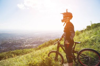 Dağların alçak bulutlar zaman aşağıda bir dağın tepesine dağ bisikleti üzerinde duran genç bir adam