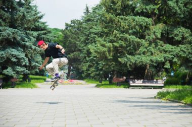 Uzun saçlı skater-genç bir tişört ve spor ayakkabı şapka fırtınalı gökyüzü karşı bir ara sokakta atlar