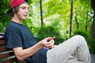 Bir kap içinde uzun saçlı bir hippi bir bankta oturur ve topluca spinner döner