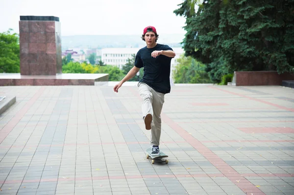 Kluk v čepici zrychluje, tlačí jeho nohu na jeho skateboard — Stock fotografie