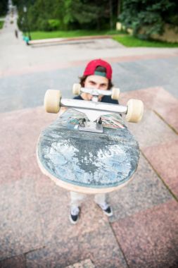 Bir kaykay üzerinde şehir manzara arka plan ile genç bir patenci duruyor