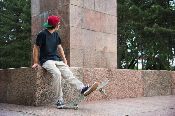 Skater siede con la schiena e pensa accanto allo skateboard — Foto Stock