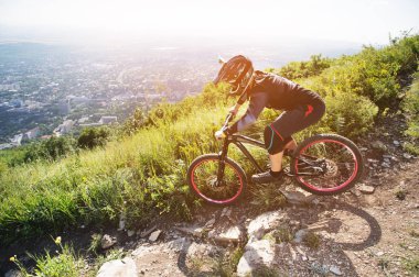 Bir binici bir kask içinde bir çakıl yol boyunca bir dağ bisikleti dağ yamacı biniyor