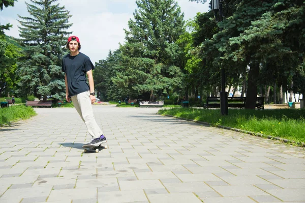 Długowłosy nastolatek skater w T-shirt i czapkę sneaker skacze aleja przeciwko burzliwe niebo — Zdjęcie stockowe