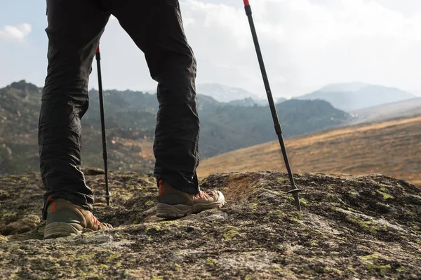 Κοντινό πλάνο του αρσενικό πόδια σε μπότες πεζοπορία με ραβδιά για Nordic walking το φόντο των βράχων και μακρινές χώρες του Καυκάσου — Φωτογραφία Αρχείου
