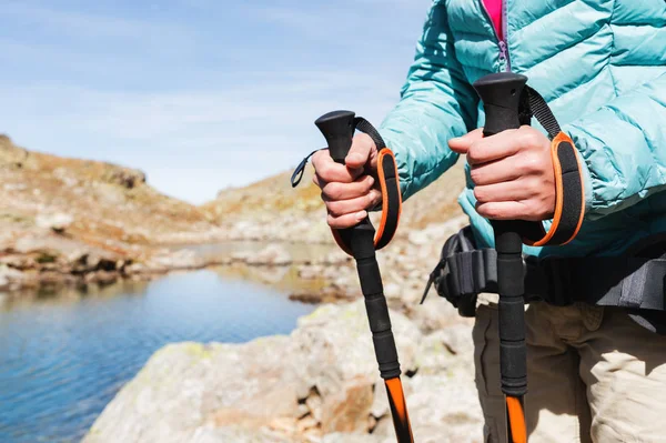 Detail ženských rukou s Trekingové hole pro Nordic walking na pozadí alpské jezero a daleké kavkazské skály — Stock fotografie