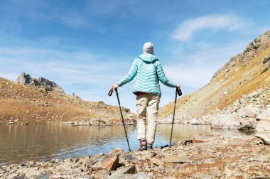Kafkas Dağları'nda yüksek dağ gölü yüksek sopa izleme ile bir ince kız backpacker standları
