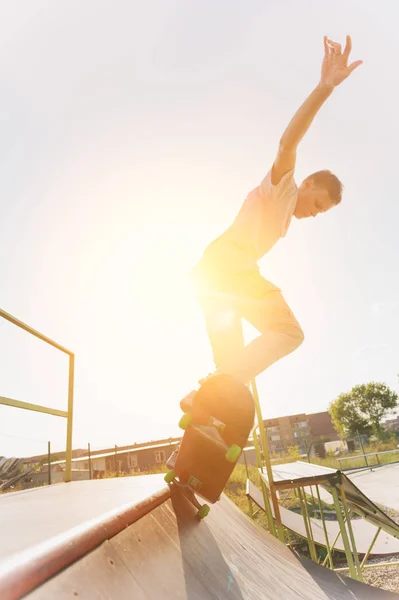 Adolescente skatista pendurar sobre uma rampa em um skate em um parque de skate — Fotografia de Stock