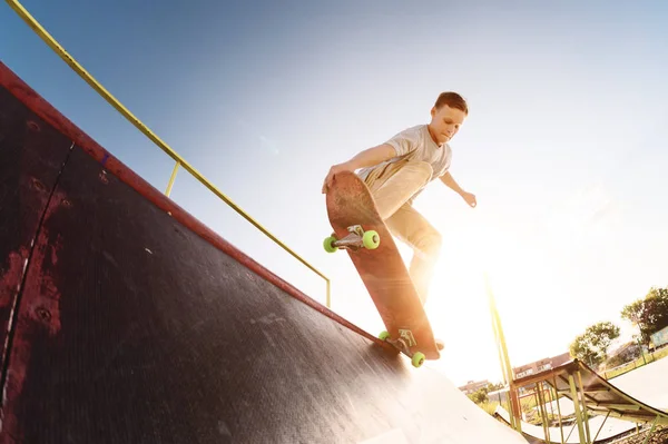Adolescente skatista pendurar sobre uma rampa em um skate em um parque de skate — Fotografia de Stock