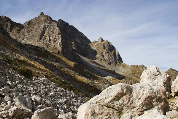 Rocas afiladas de alta montaña contra el cielo azul y las nubes blancas. Cáucaso —  Fotos de Stock