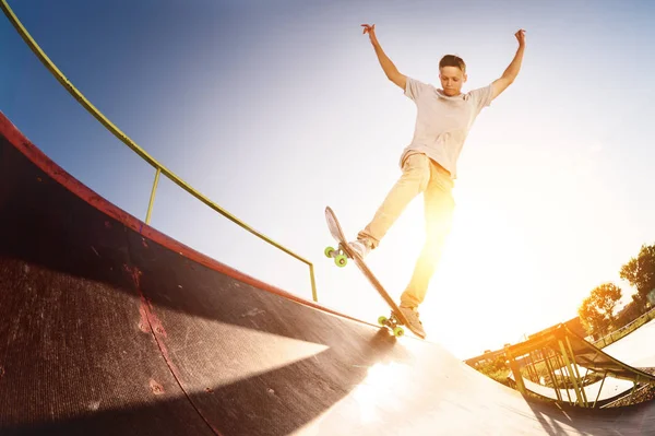 Έφηβος σκέιτερ κλείσεις πέρα από μια κεκλιμένη ράμπα σε ένα skateboard σε ένα πάρκο skate — Φωτογραφία Αρχείου