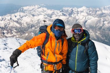 Portre tırmanıcı bir aşağı ceket ve emniyet kemeri o arkadaşı karla kaplı bir dağın tepesine giderken yanında duruyor