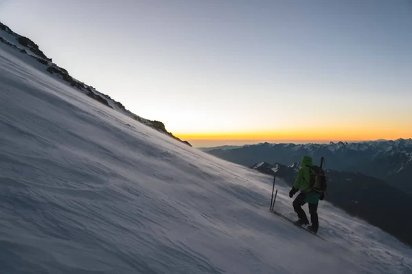 Klimmer bij zonsopgang vroege ochtend wandelingen op de helling en op de grond boven de sneeuw sweeps drifting snow — Stockfoto