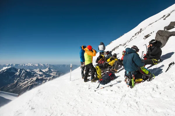 Volledig ingerichte professionele bergbeklimmers op een stop-sit op een besneeuwde helling bij zonnig weer. — Stockfoto