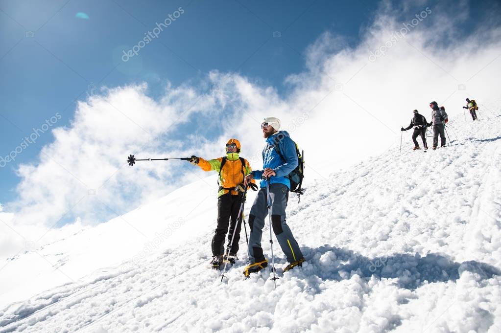 fully equipped Professional climbers descend down the snowy slope in sunny weather