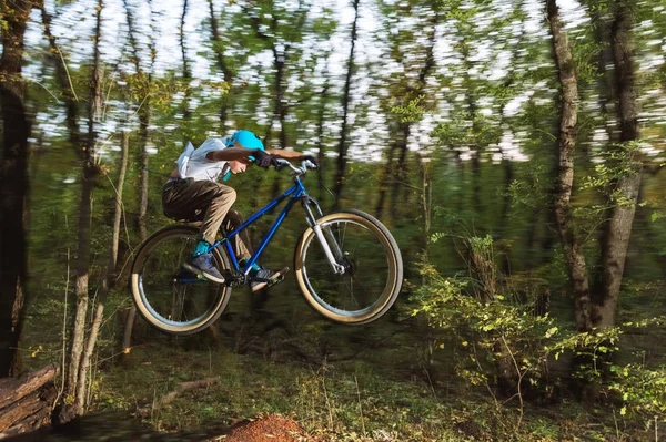 Молодой парень в шлеме летает на велосипеде после прыжка с кикера — стоковое фото