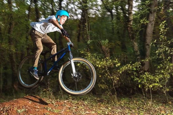 Un ragazzo con il casco vola in bicicletta dopo essere saltato da un kicker — Foto Stock