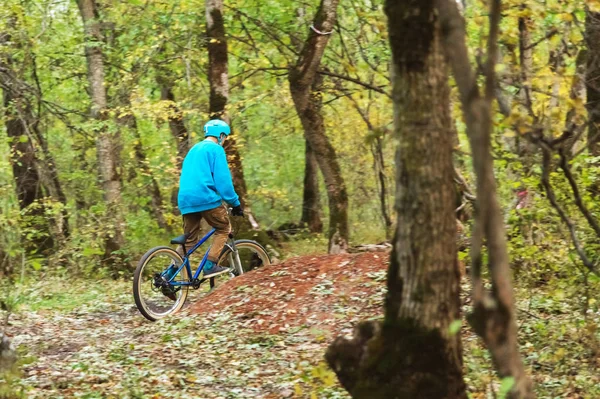 Un giovane cavaliere che guida una mountain bike va a velocità in discesa nella foresta autunnale . — Foto Stock