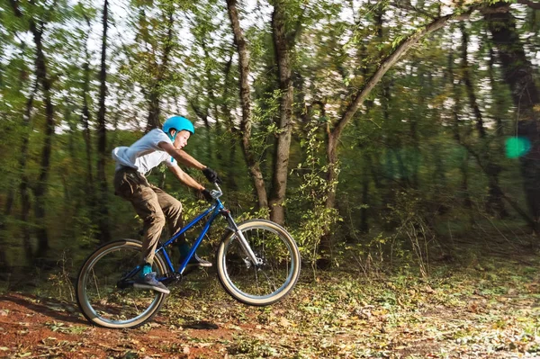 Un ragazzo con un casco vola atterrato su una bicicletta dopo essere saltato da un kicker — Foto Stock