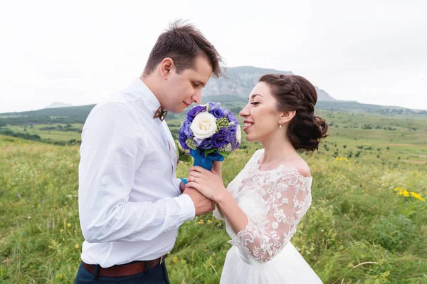 Un par de recién casados de pie en un abrazo de brazos en la naturaleza — Foto de Stock