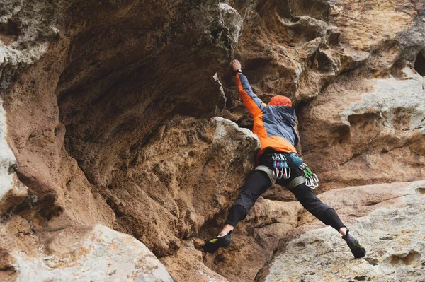 Хипстер - альпинист в возрасте восхождения на красивую скалу без страховки и шлема — стоковое фото