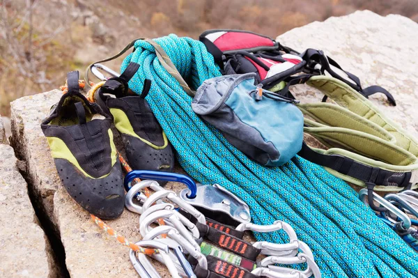 Equipo de escalada: la cuerda y las carabinas se ven desde el primer plano lateral. Una cuerda trepadora enrollada tendida en el suelo como fondo. Concepto de deporte al aire libre — Foto de Stock