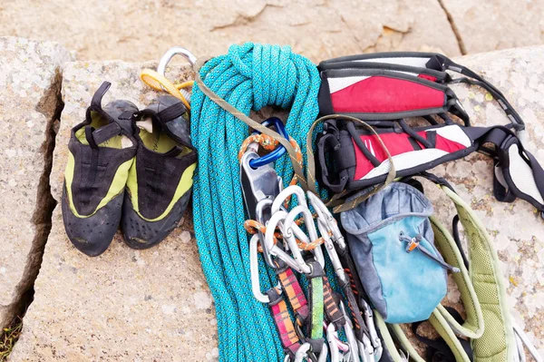 Equipo de escalada - cable y carabinas vista desde el primer plano superior. Una cuerda trepadora enrollada tendida en el suelo como fondo. Concepto de deporte al aire libre — Foto de Stock