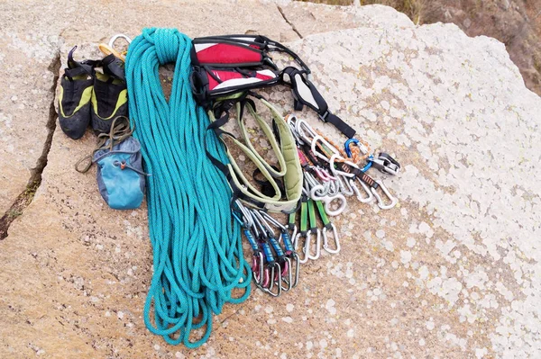 Equipo de escalada - cable y carabinas vista desde el primer plano superior. Una cuerda trepadora enrollada tendida en el suelo como fondo. Concepto de deporte al aire libre — Foto de Stock