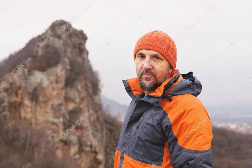 Portrait of a rock climber aged and with a beard against the backdrop of sharp mountain in the northern Caucasus