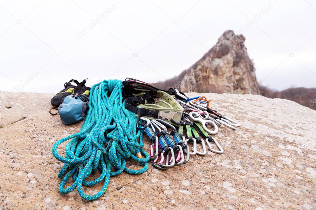 Climbing equipment - rope and carbines view from the side close-up. A coiled climbing rope lying on the ground as a background. Concept of outdoor sport