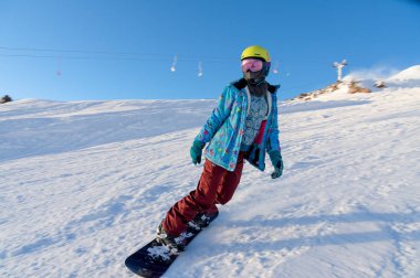 Dağ Elbrus, Rusya Federasyonu - 30 Kasım 2017: Alp yokuş aşağı güneş maske ve bir eşarp giyen bir snowboard Kız biniyor. Kışın dağlarda kalan kavramı.